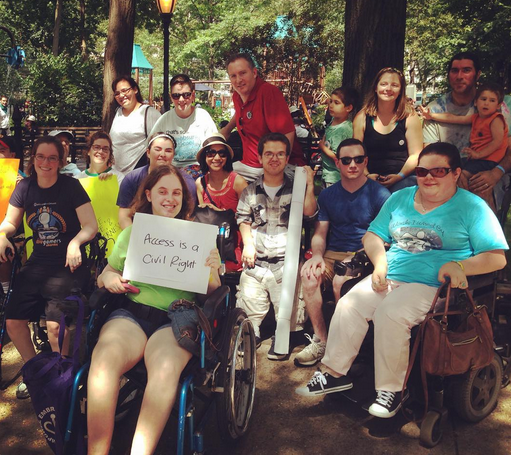 A group of people taking a picture together while one is holding a sign saying "access is a civil right"