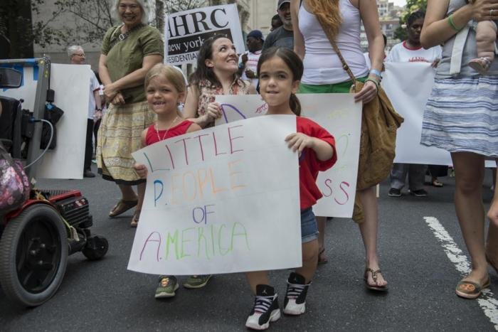 Two people holding a sign "Little People of America"