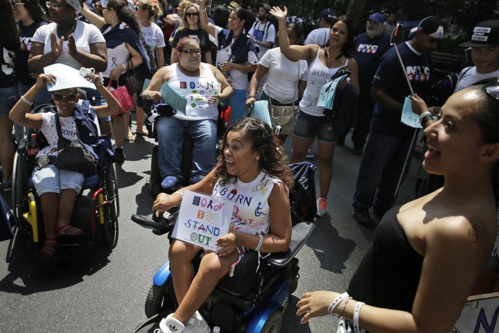 Spectators wave as a float passes by before the start of the inaugural Disability Pride Parade.