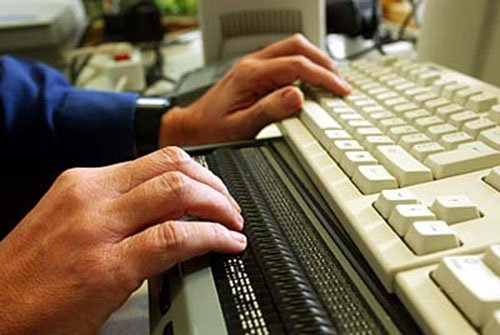 Hands on computer keyboard and modular braille display. Photo: European Commission