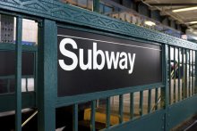 An image of a subway sign on the side of entrance