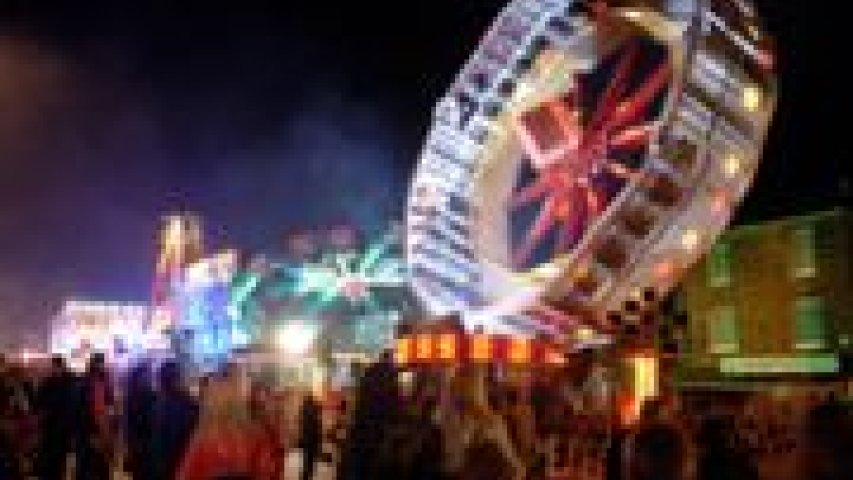 A large crowd of people in front of a carnival ride.