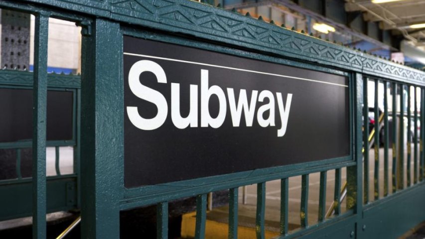 An image of a subway sign on the side of entrance