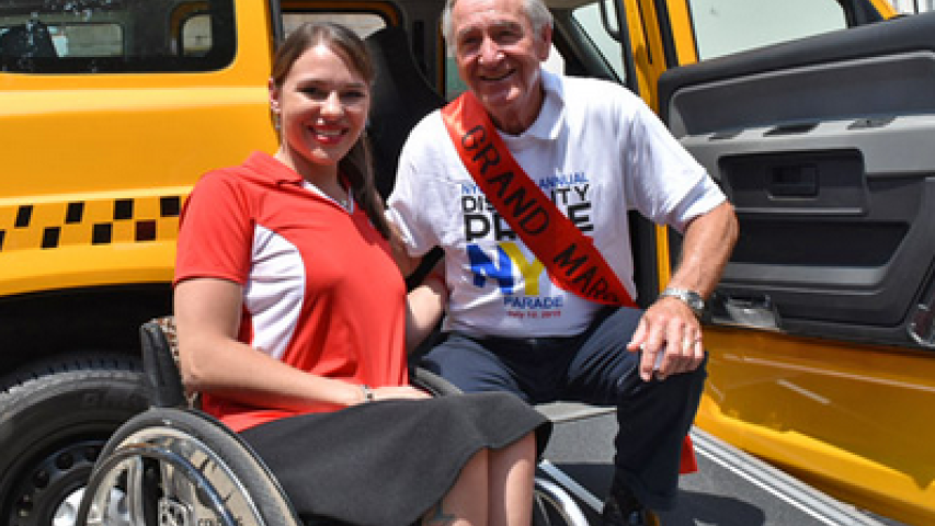 A woman in a wheelchair taking a picture with the Grand Marshal of the parade, Tom Harkin.