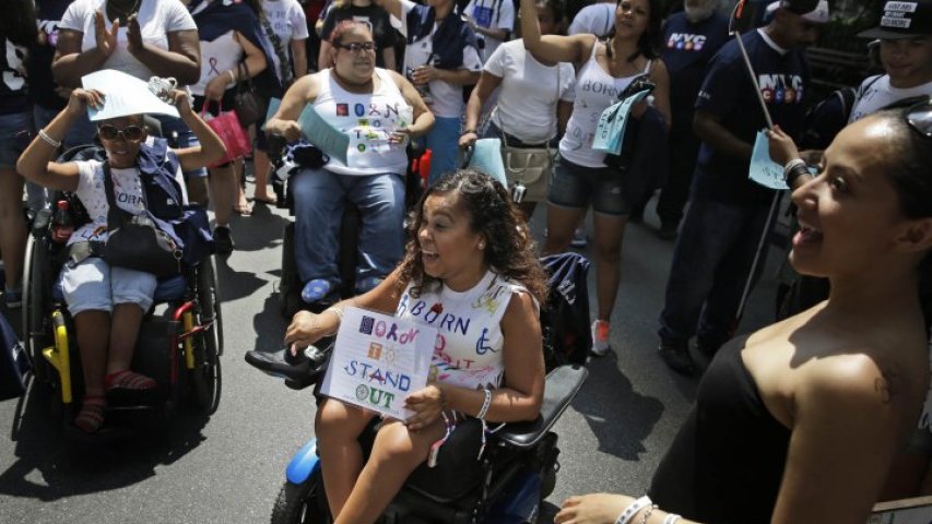 Spectators wave as a float passes by before the start of the inaugural Disability Pride Parade.